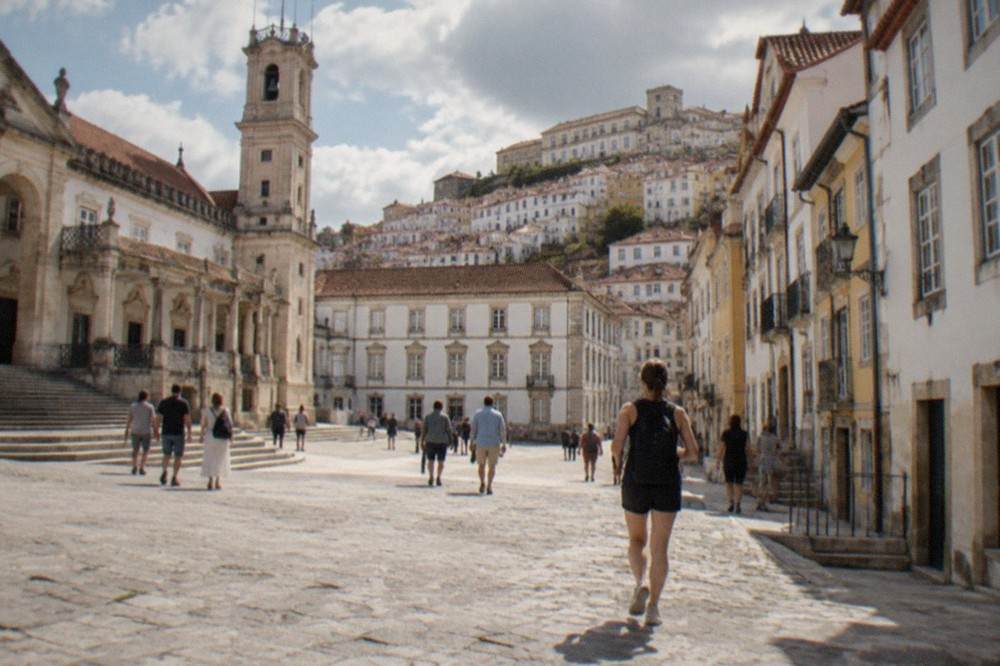 Visitors walking through the cobbled square in front of the old university buildings in Coimbra