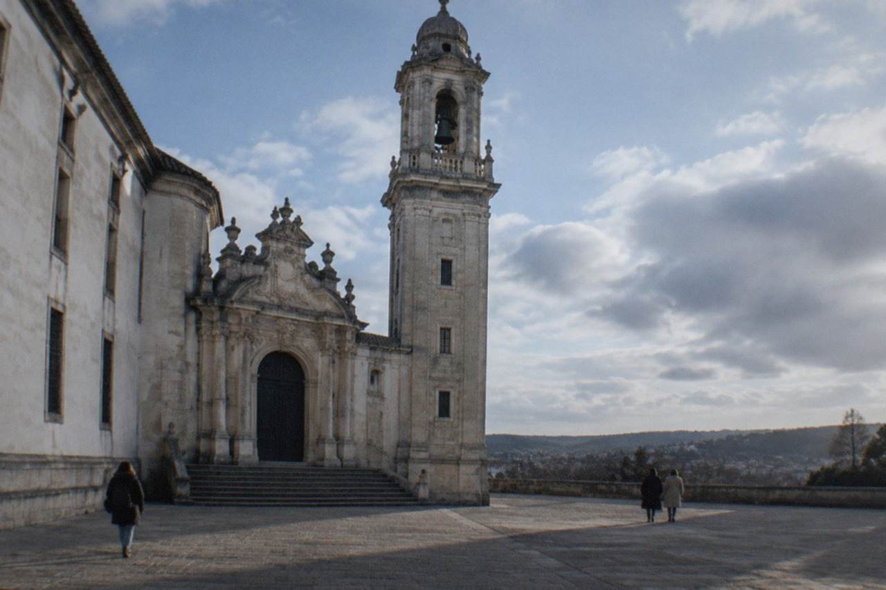 The ornate baroque doorway and bell tower of the University of Coimbra seen from the paved courtyard on the university hill