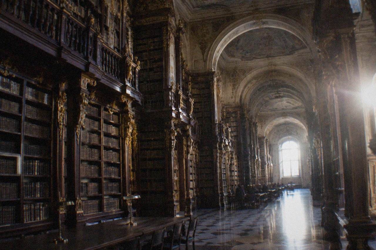 The ornate gilded interior of the Joanina Library in Coimbra with tall wooden bookshelves