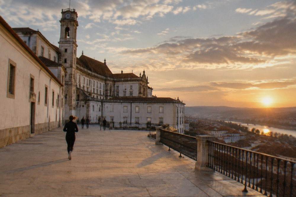 The baroque tower and palace walls of the University of Coimbra seen from the narrow streets below the hill