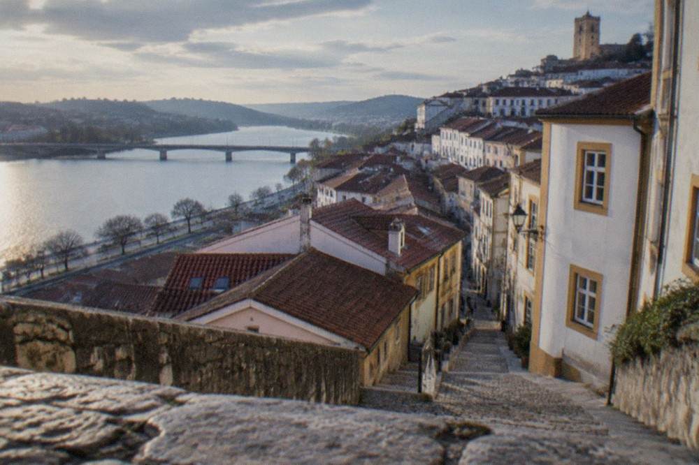 The rooftops and riverfront of Coimbra, Portugal, seen from the upper town on a clear day