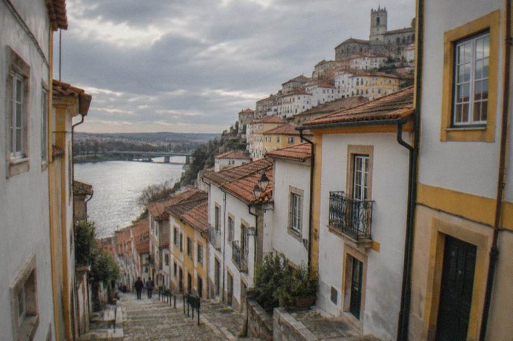 Narrow cobbled lane in Coimbra's old town sloping down toward the River Mondego