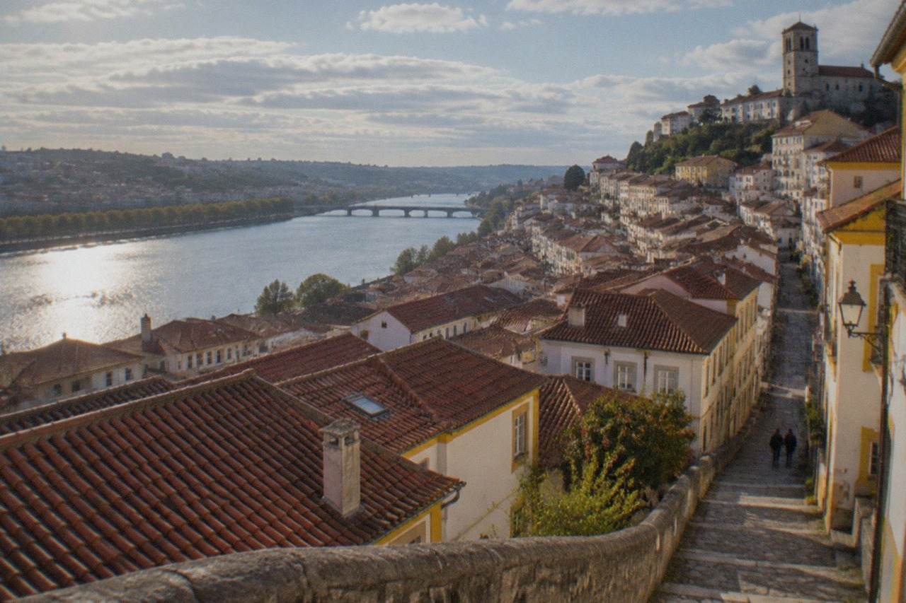 View over Coimbra's old town rooftops toward the River Mondego on a bright morning