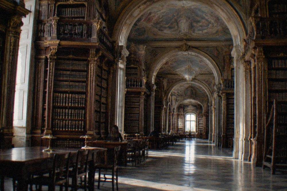 The baroque interior of the Biblioteca Joanina with its painted ceilings and tall wooden bookshelves