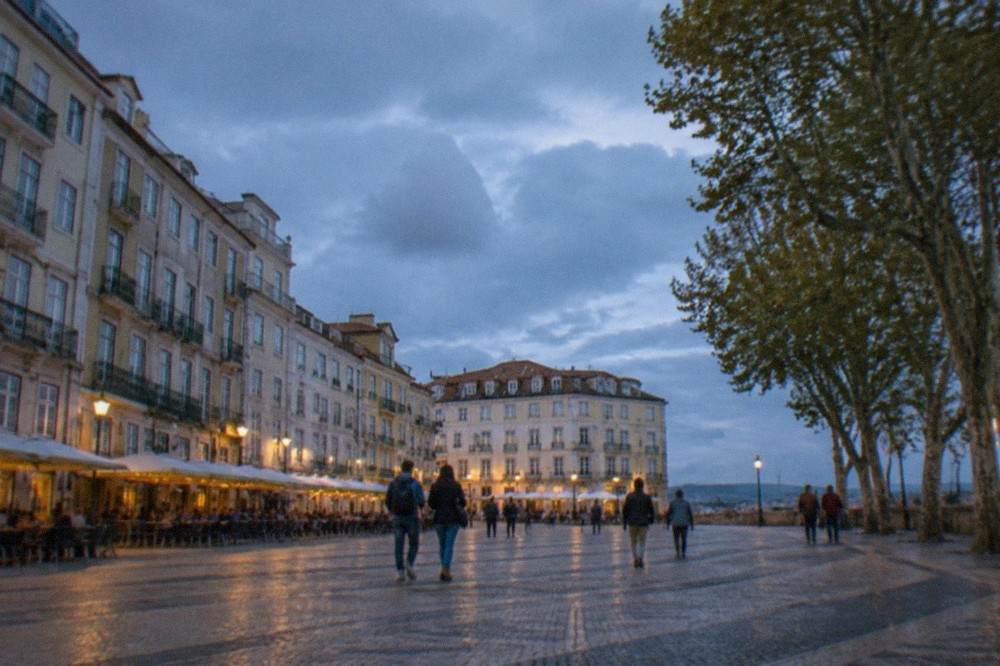 Visitors walking on a cobbled street in Coimbra's old town below the university hill
