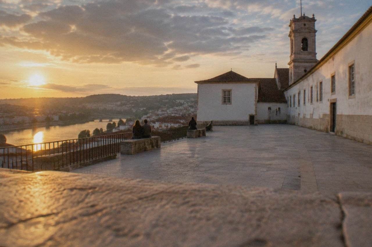 The historic University of Coimbra buildings on the hill above the River Mondego at golden hour