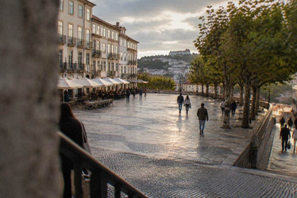 Visitors walking the cobbled lane below the university hill in warm late afternoon light