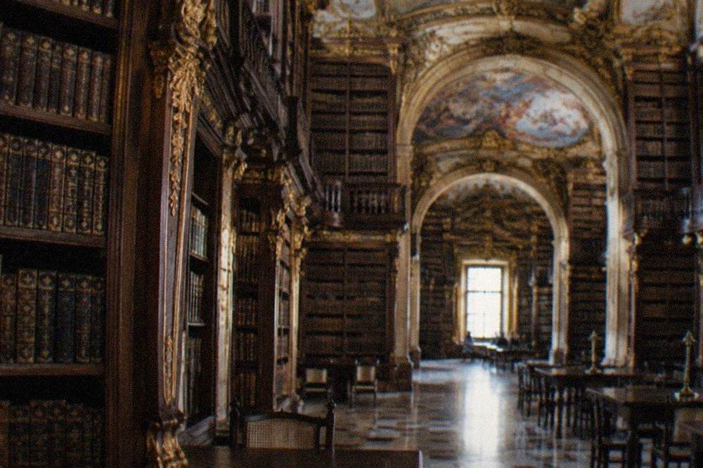 The gilded baroque interior of the Joanina Library with its tall wooden bookshelves and painted ceiling