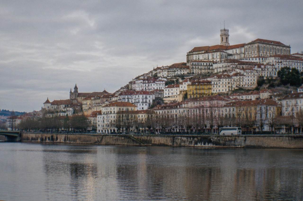 The hillside city of Coimbra in Portugal seen from across the River Mondego, with the university buildings rising above the old town rooftops