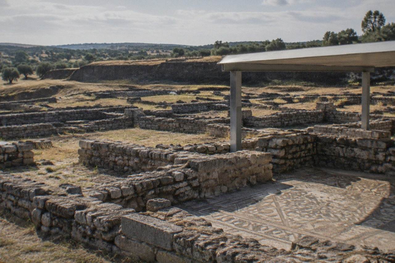 Roman stone walls and foundations of the Conimbriga archaeological site under a clear sky