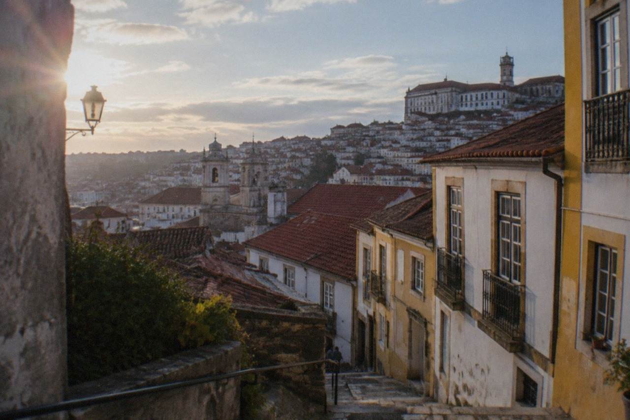 A view over the tiled roofs and church towers of a Portuguese city under an afternoon sky