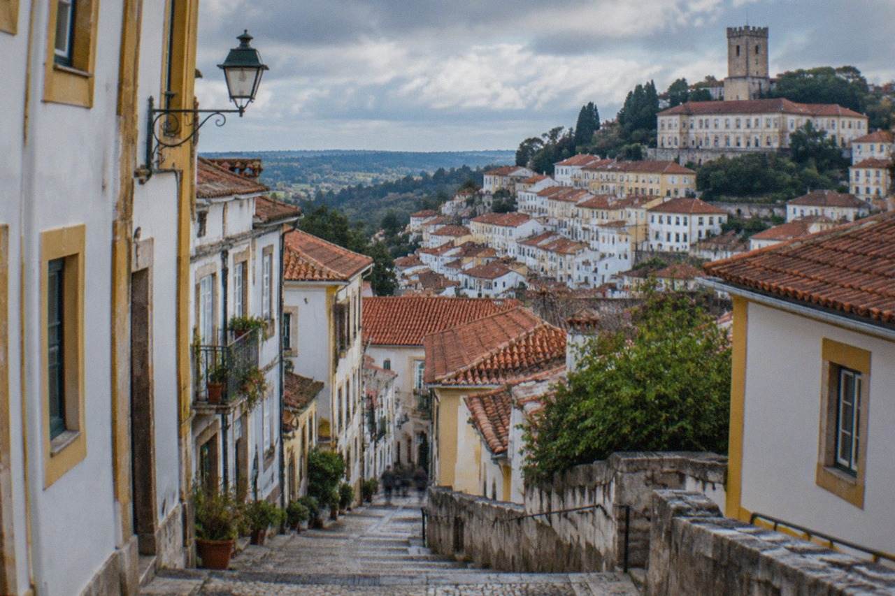 A walled hill town with white houses and a stone castle tower above surrounding countryside