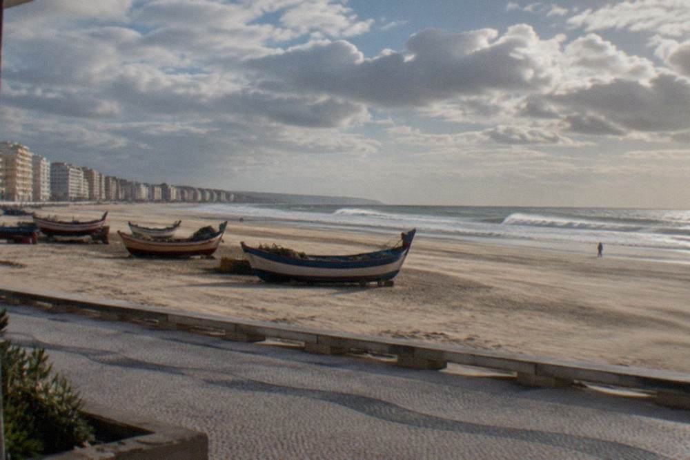 Fishing boats drawn up on a wide sandy beach beside colourful seaside houses