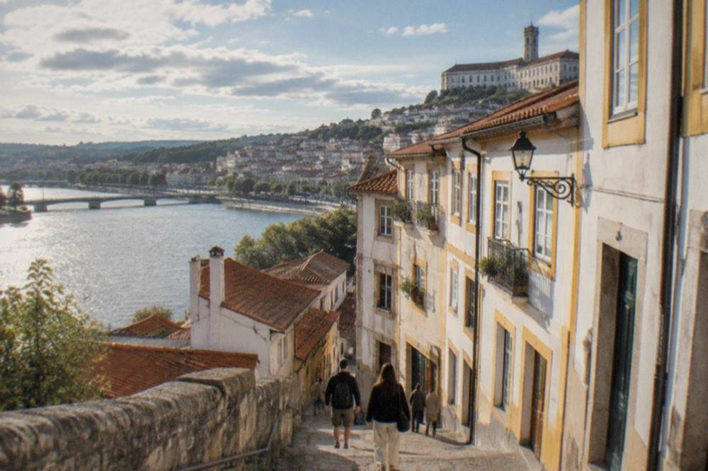 Visitors walking down a narrow steep lane in Coimbra's old town towards the River Mondego