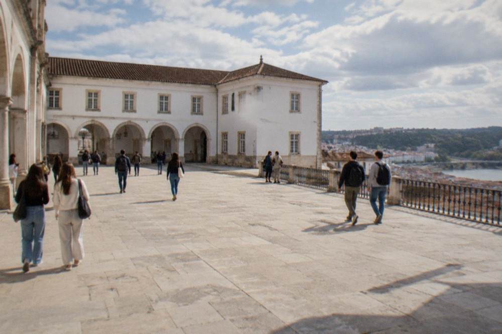 Students and visitors walking through the stone arches and courtyard of the University of Coimbra