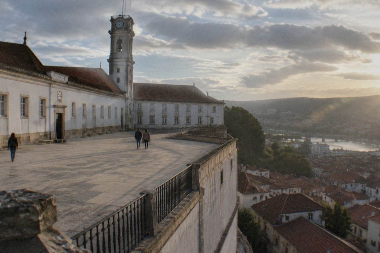 The walled courtyard and tower of the University of Coimbra above the red rooftops of the old town