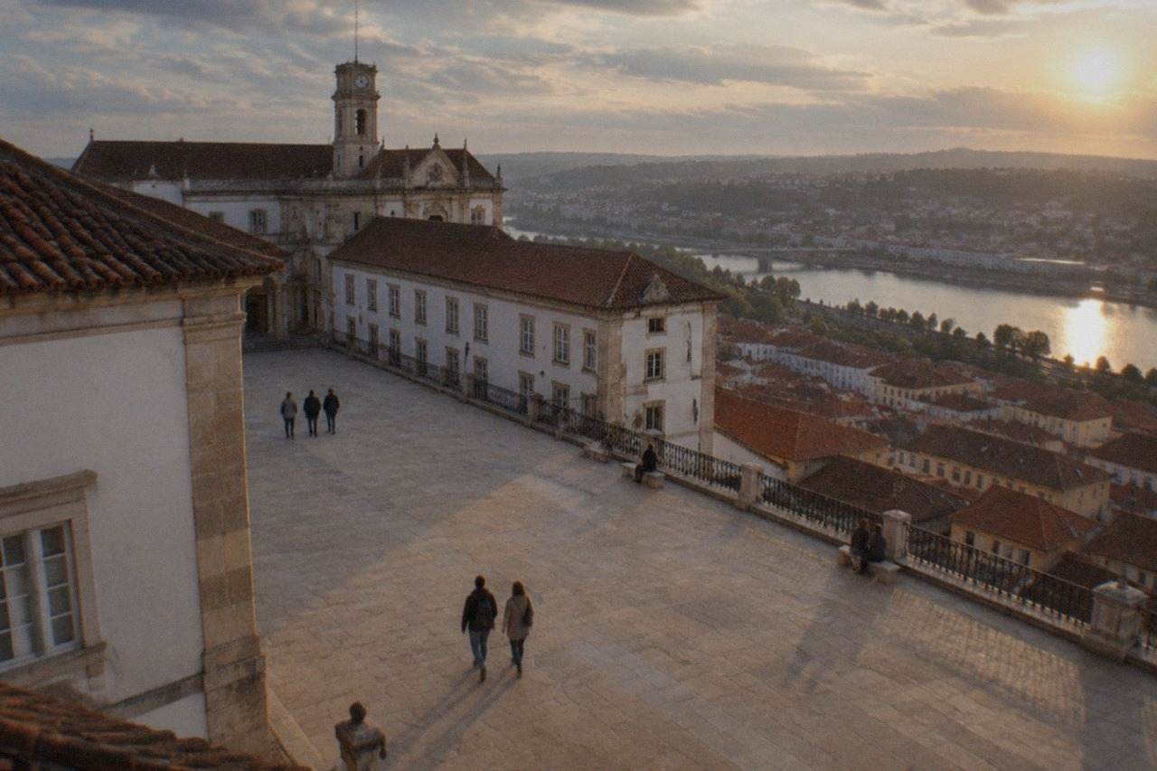 The University of Coimbra's Paço das Escolas seen from the old town rooftops, with the Mondego river valley behind