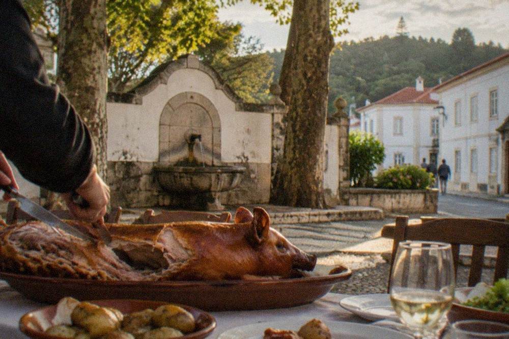 Roast suckling pig being carved at a Portuguese table