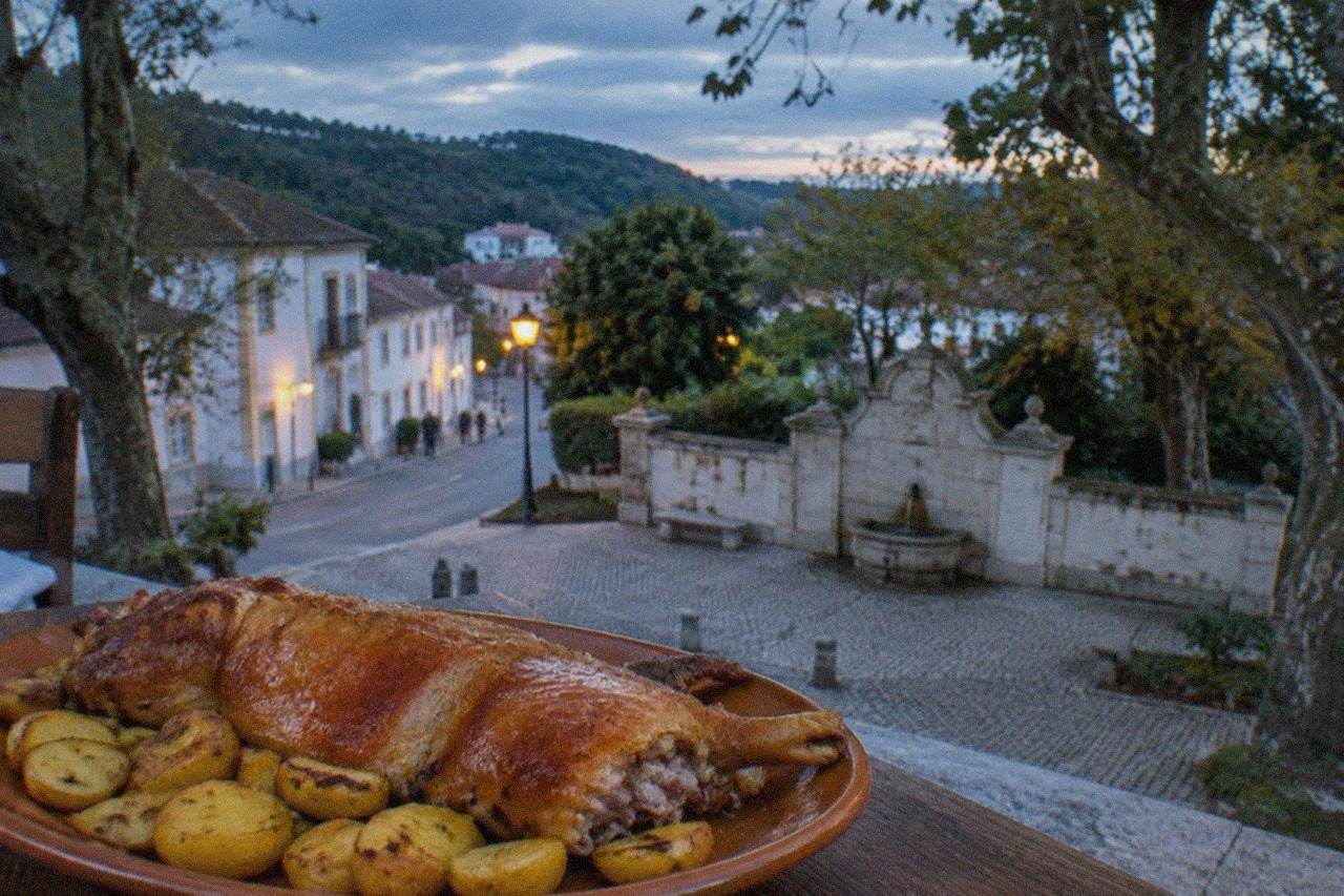 A plate of golden roast suckling pig with crispy skin, served with potatoes in a rustic restaurant
