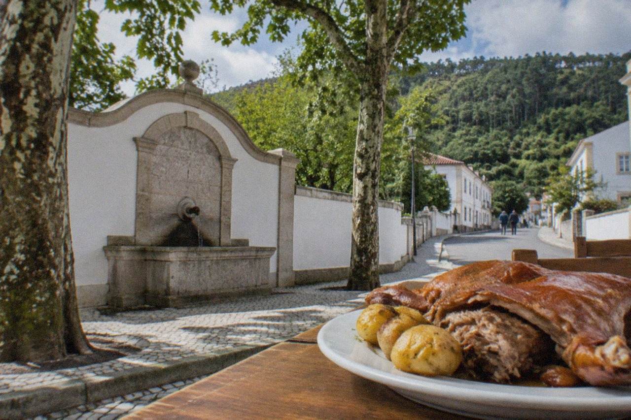 A plate of roasted suckling pig served at a wooden table in a traditional Portuguese restaurant