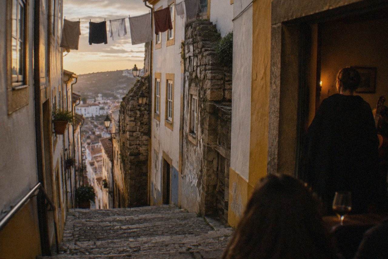A singer in a black academic cape performing fado in a dimly lit room in Coimbra