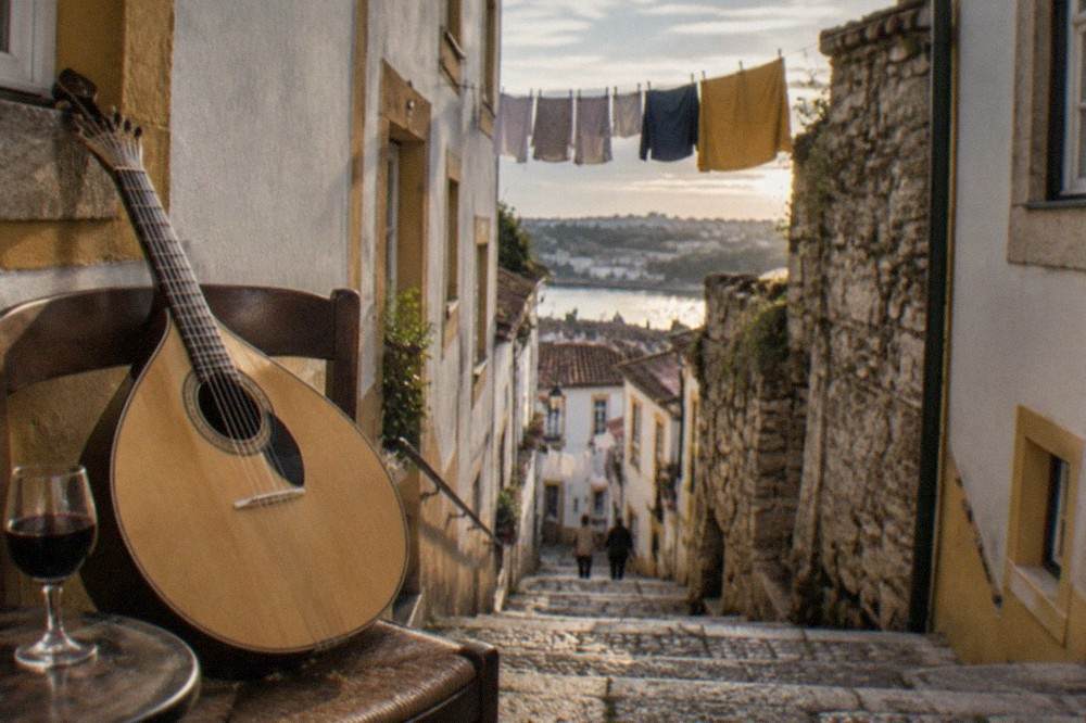 A Portuguese guitarra resting on a chair beside a glass of port wine before a fado performance