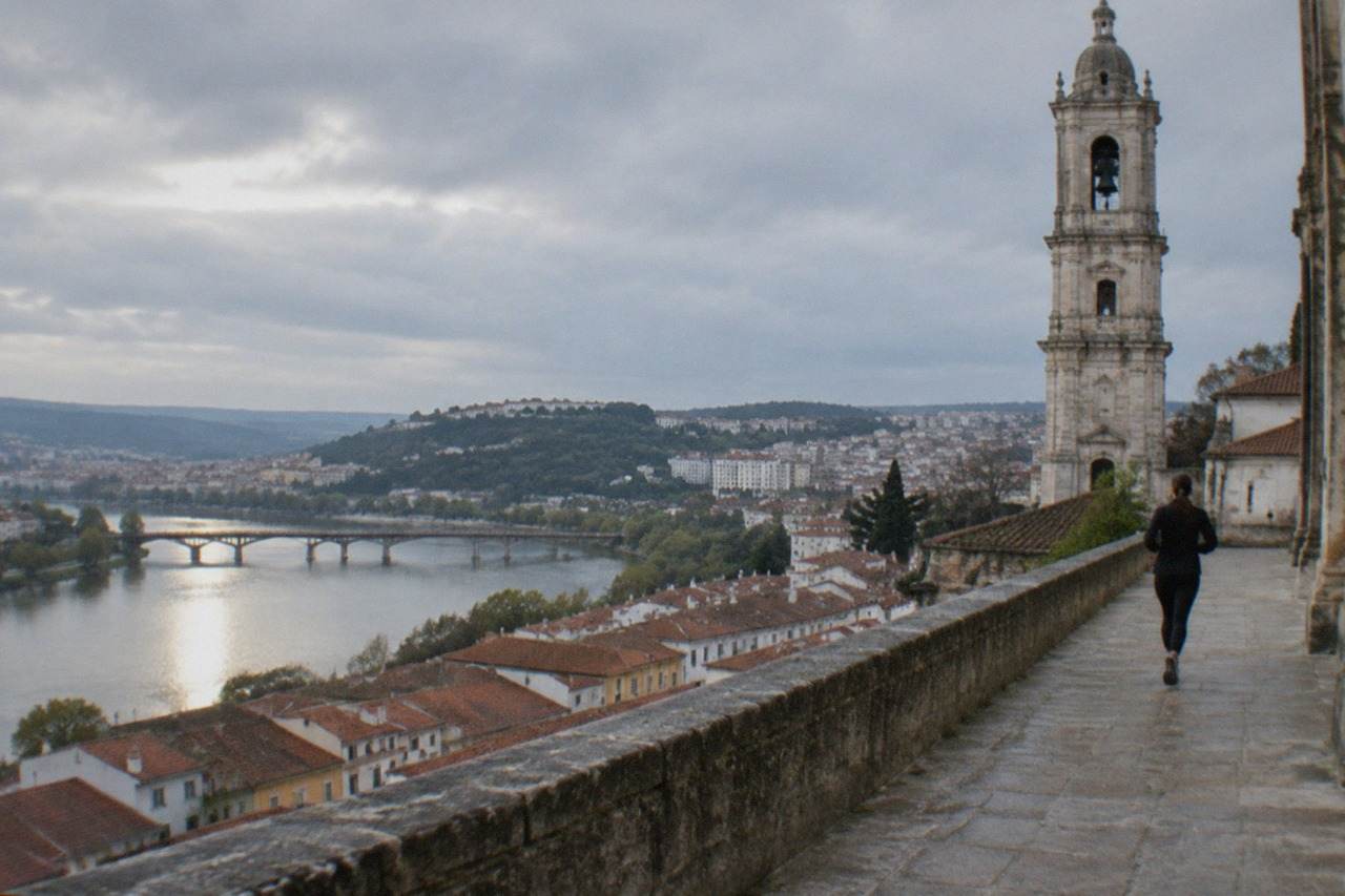 The hillside of Coimbra with the university tower rising above red rooftops and the River Mondego below