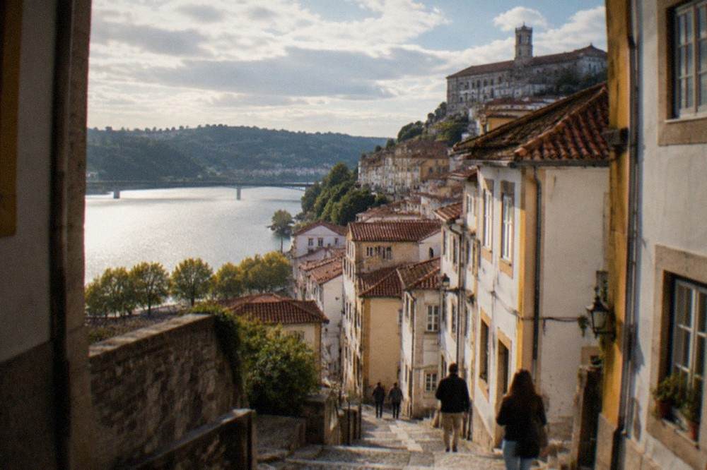 Visitors walking down the narrow cobbled streets of Coimbra's old town towards the river