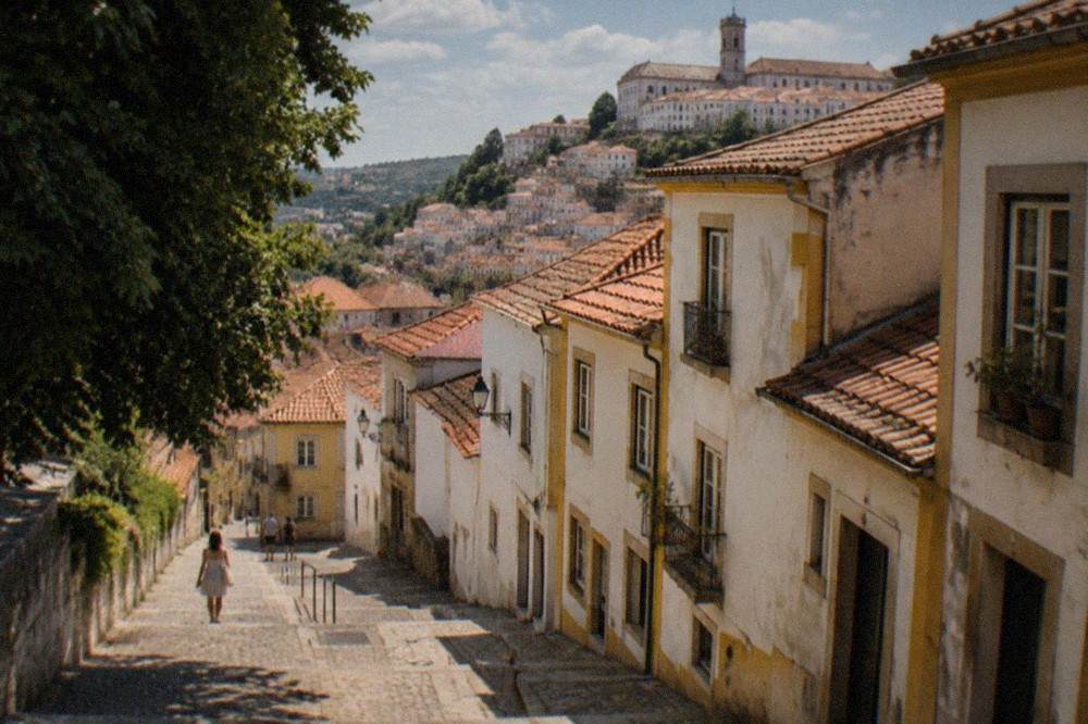 A quiet cobbled street in Coimbra's old town in warm late-summer light with few people around