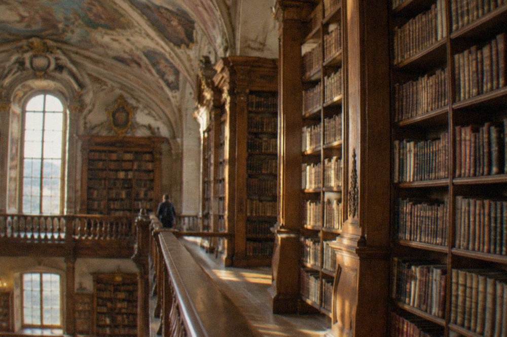 The baroque interior of a historic Portuguese library with tall wooden bookshelves and painted ceilings