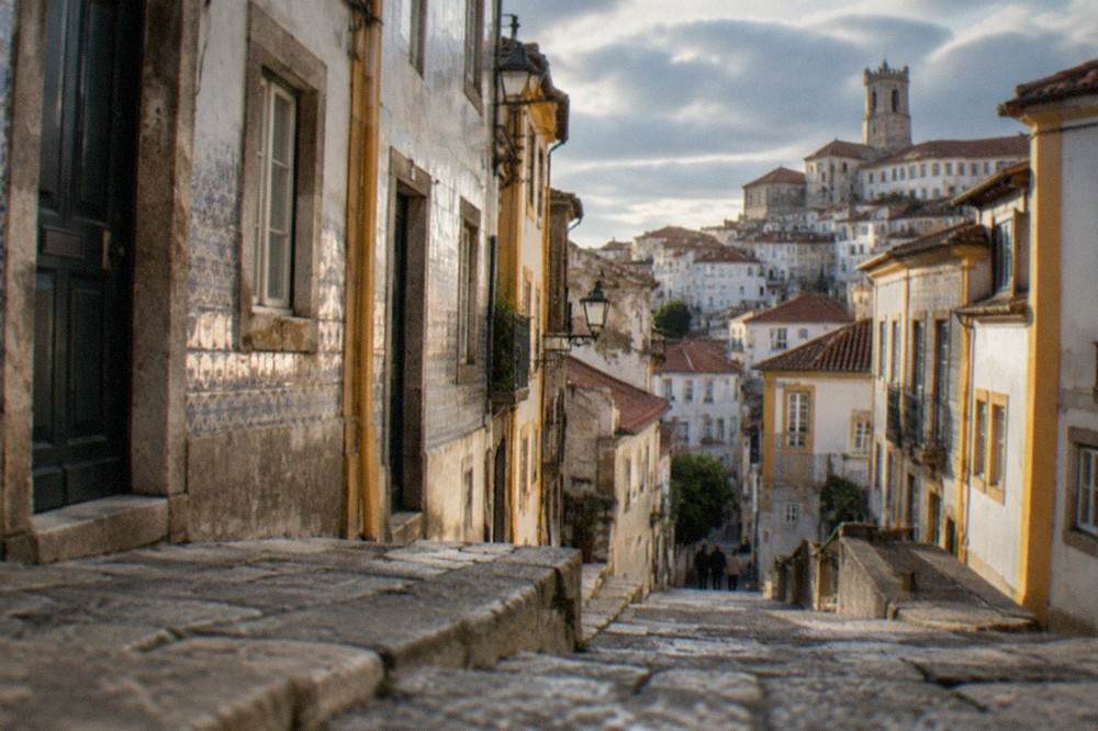 A quiet lane of tiled facades in Coimbra's old town in late afternoon light