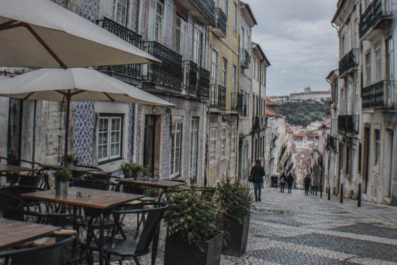 Outdoor tables of a restaurant on a sloped cobbled street in Coimbra's old town