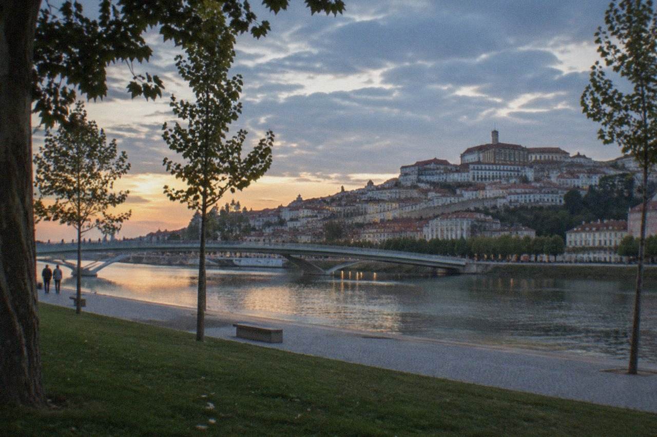 A view over the tiled rooftops of Coimbra's old town with the River Mondego in the evening light