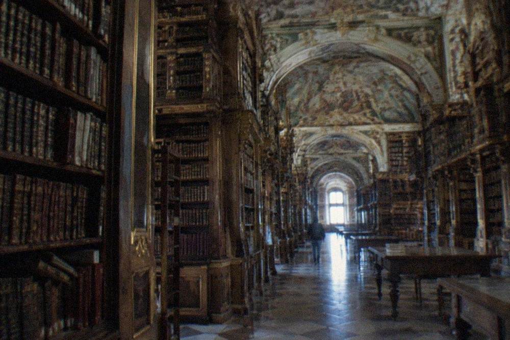 The baroque interior of the Biblioteca Joanina, with tall wooden bookshelves and painted ceilings