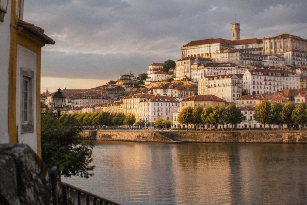 The old university buildings and tower of Coimbra seen from across the River Mondego at golden hour