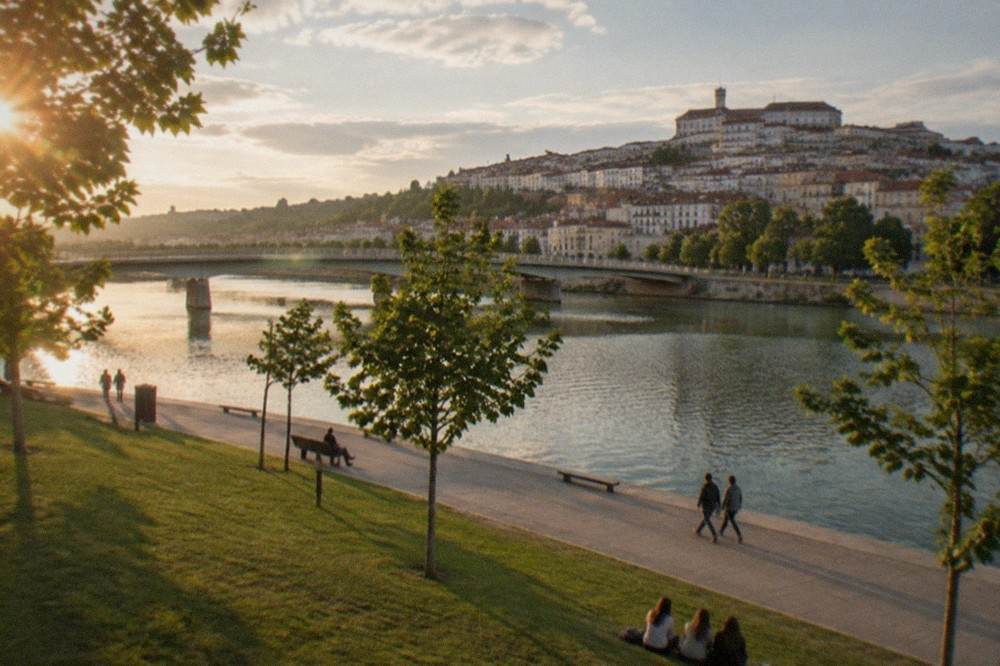 The Mondego riverside promenade in Coimbra with the old town rising on the far bank