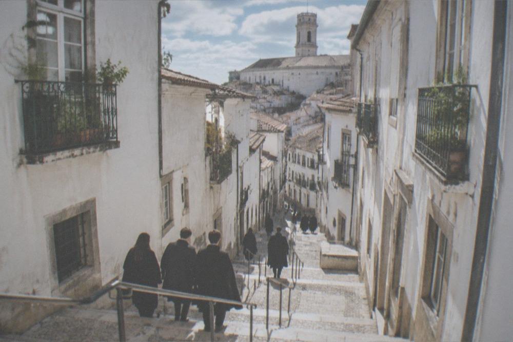 Students in black academic capes walking through the university square