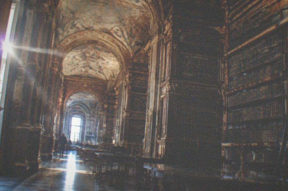 The baroque interior of the Joanina Library with tall wooden bookshelves and painted ceilings