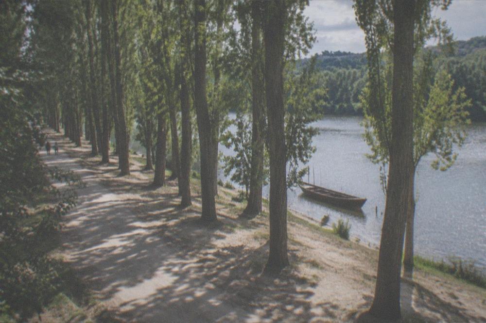A small traditional wooden boat moored on a wide river with a forested bank behind it