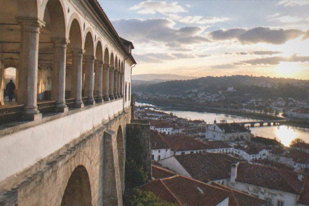 An evening view over the rooftops and river of a Portuguese university city from a high terrace