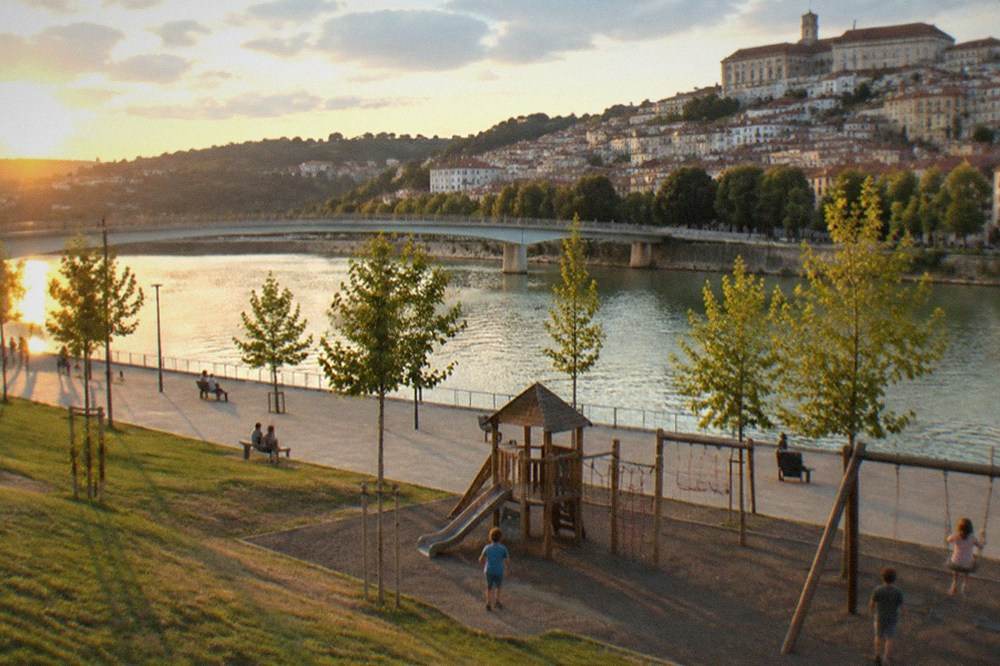 Children playing on a riverside playground with the old town bridge in the background