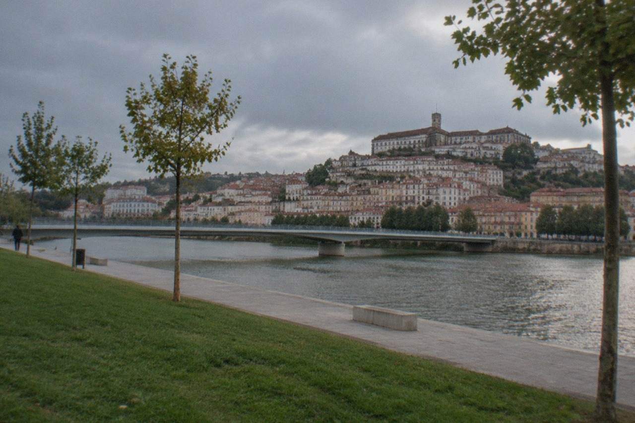 A stone terrace garden overlooking the River Mondego with the university hill and old town of Coimbra rising on the opposite bank