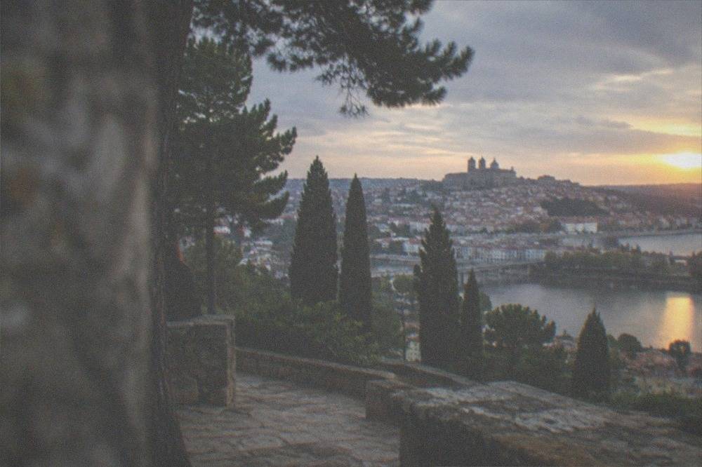 The rooftops and cathedral towers of Coimbra's old town seen across the river at golden hour