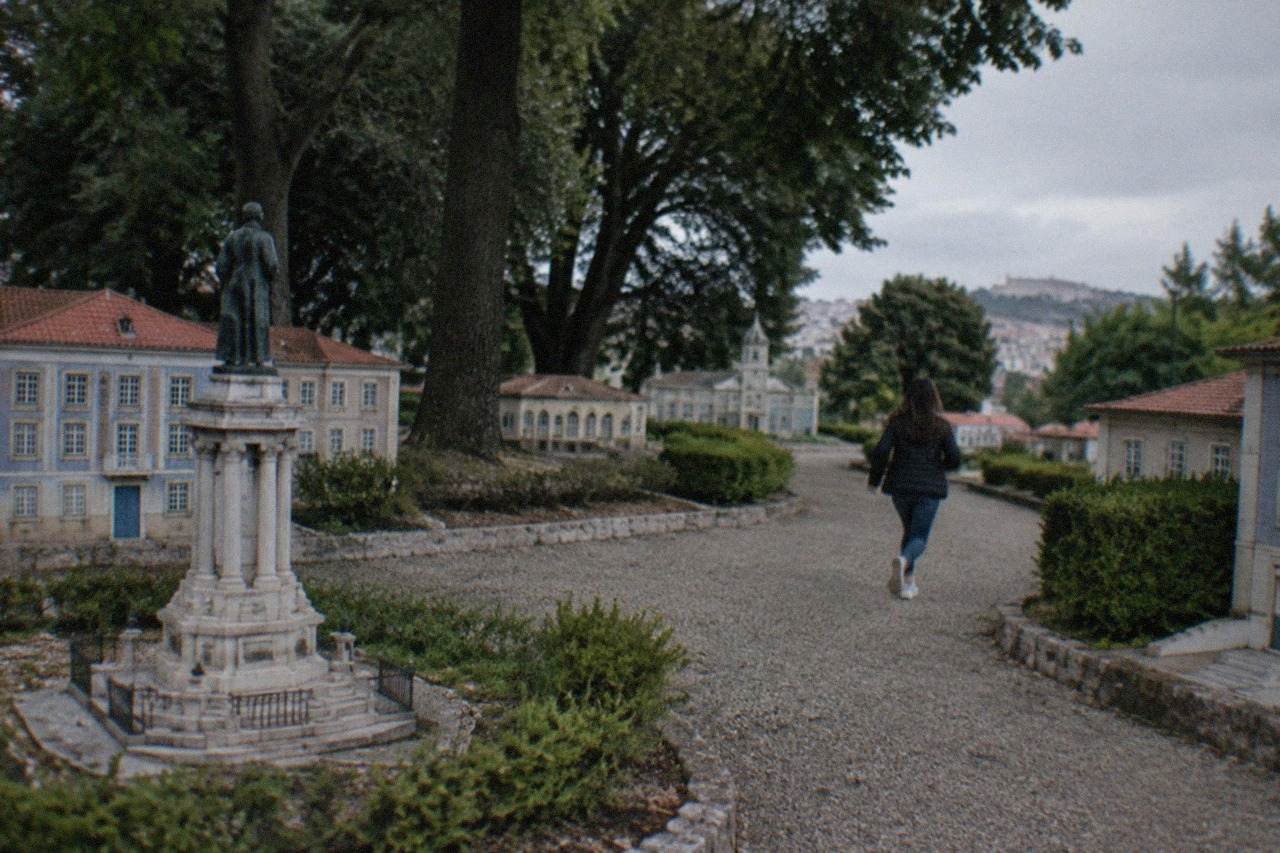 Miniature Portuguese buildings arranged in a park, with a small-scale monument in the foreground