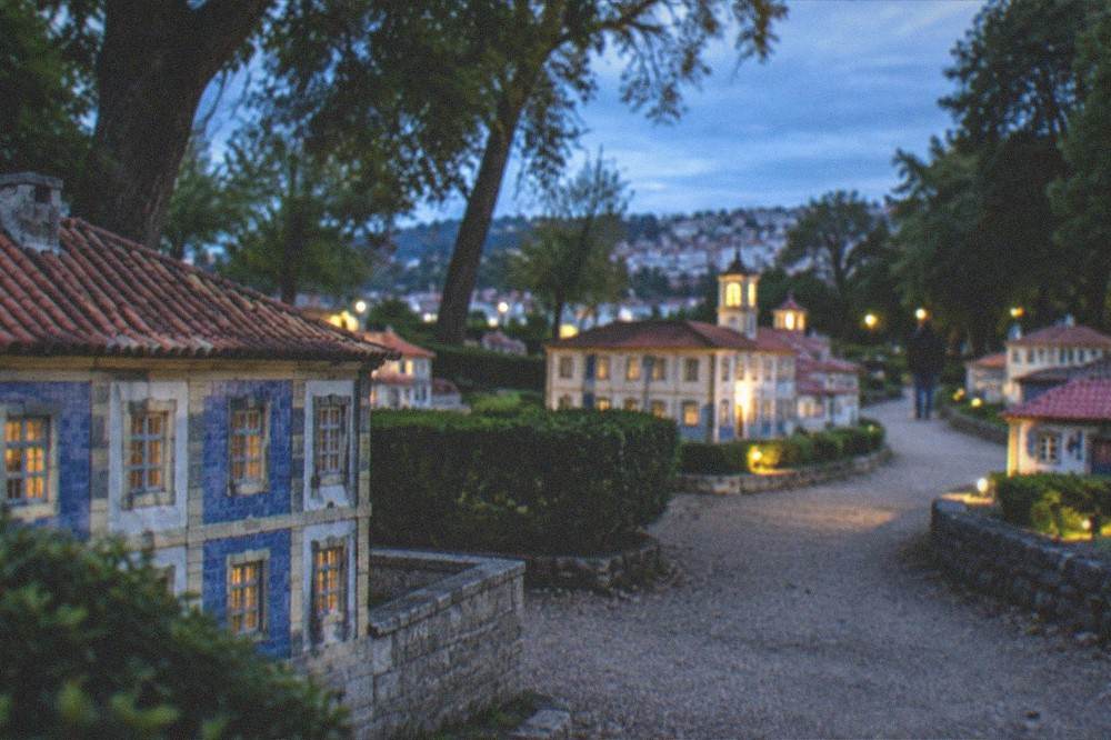 The miniature park at golden hour with small lit buildings along a path
