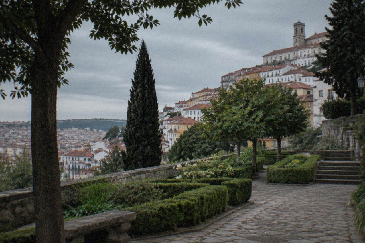 Manicured gardens and stone paths of a historic estate in Coimbra with tall trees