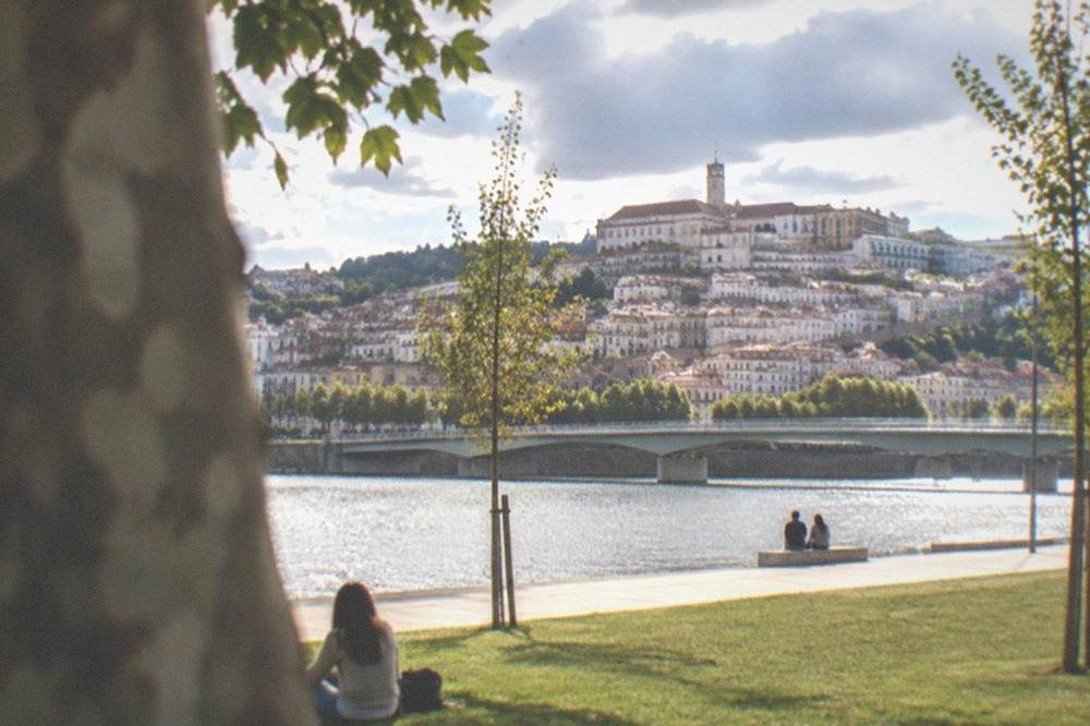 View across the River Mondego toward the old town and university buildings on a hill in Coimbra