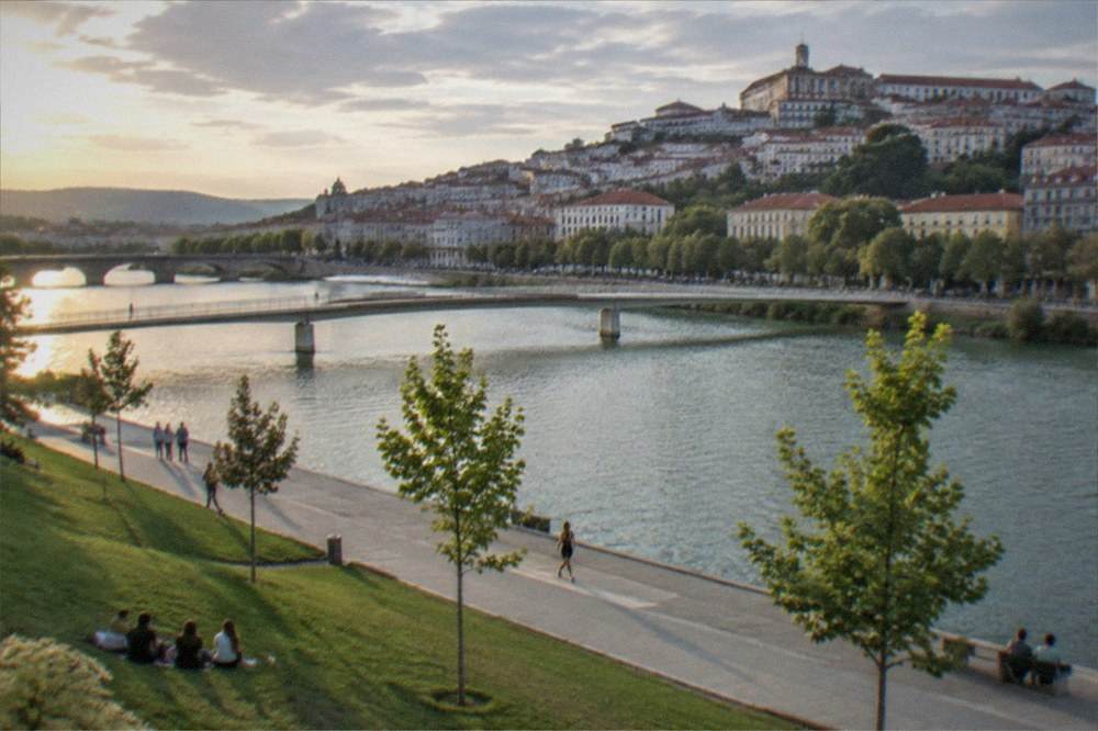 Evening light on the River Mondego with a historic bridge and city buildings behind
