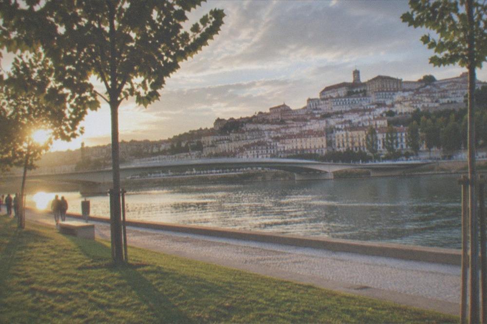 A footbridge over a wide river with a historic city skyline on the far bank