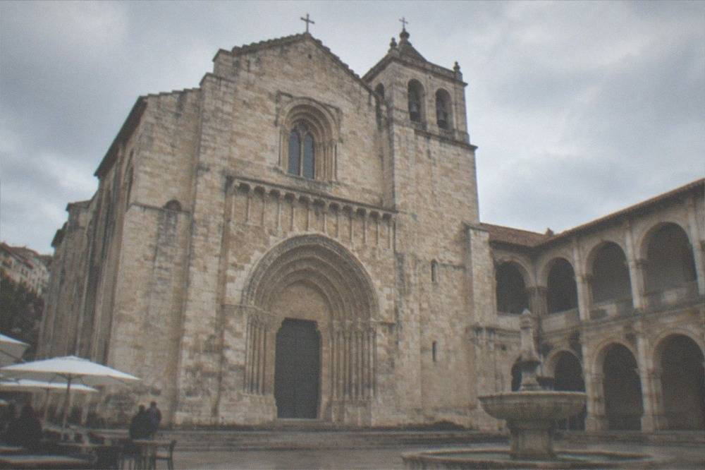 Sunlit cloister of the Santa Cruz monastery with arches and a stone fountain